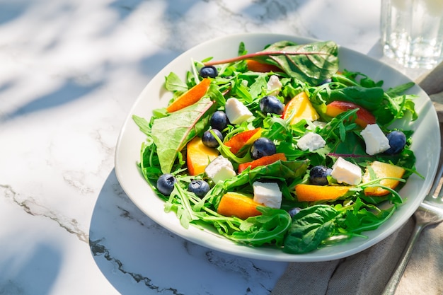 salade omemade aux bleuets nectarines roquette et fromage feta sur fond de marbre blanc