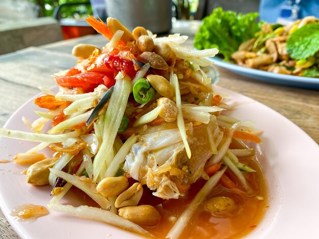 Salade de papaya épicée ou Somtum en langue thaïlandaise servie sur la table