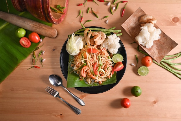 Salade de papaye ou Som tum et riz gluant sur fond de bois Cuisine traditionnelle thaïlandaise