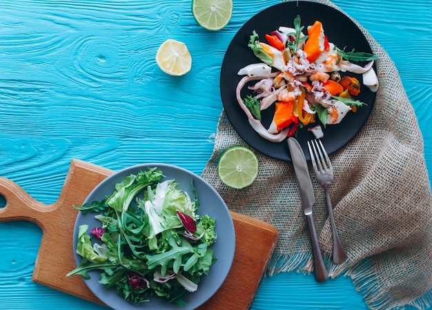 Salade et pâtes aux fruits de mer sur fond bleu