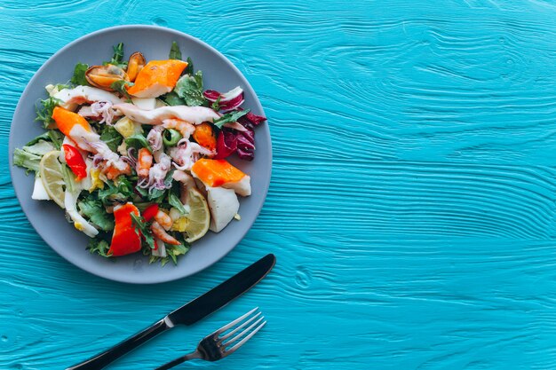 Salade et pâtes aux fruits de mer sur fond bleu