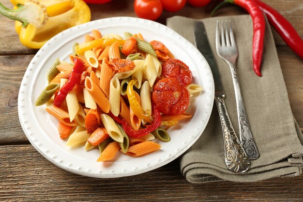 Salade de pâtes aux poivrons, carottes et tomates sur table en bois