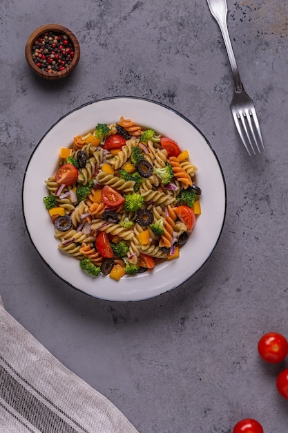 Salade de pâtes à la tomate, brocoli, olives noires. Vue de dessus