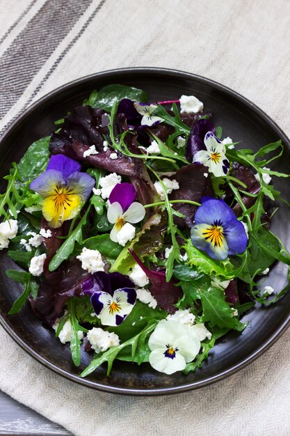 Salade de pensées et d'herbes assaisonnées d'huile végétale, de jus de citron et d'épices.