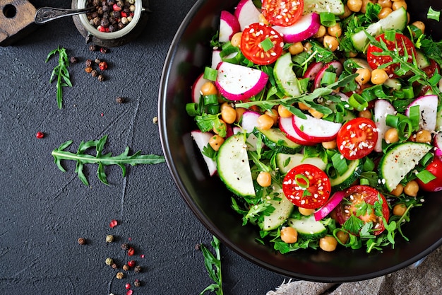 Salade de pois chiches, tomates, concombres, radis et légumes verts. Aliments diététiques. Salade végétalienne. Vue de dessus. Mise à plat