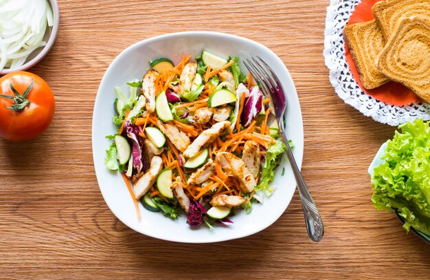 Salade de poitrine de poulet avec courgettes et tomates cerises, sur une surface en bois