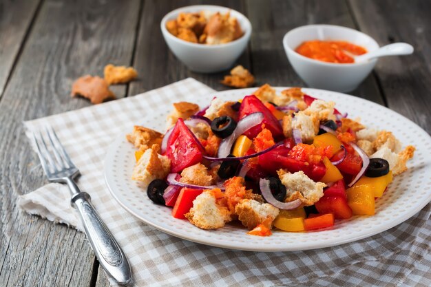 Salade de poivrons, tomates, oignons, olives et croûtons avec surface en bois ancien sousomna