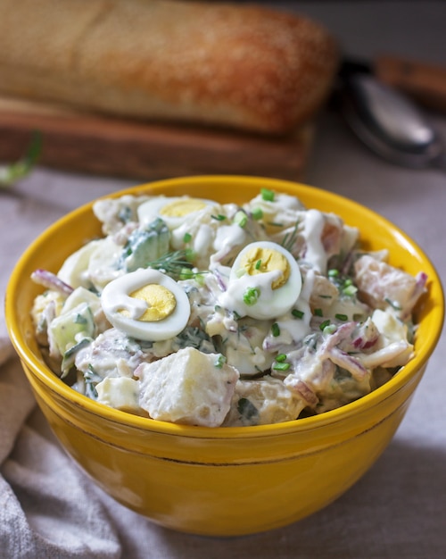 Salade de pommes de terre américaine traditionnelle avec œuf et mayonnaise, servie avec du pain. Style rustique.