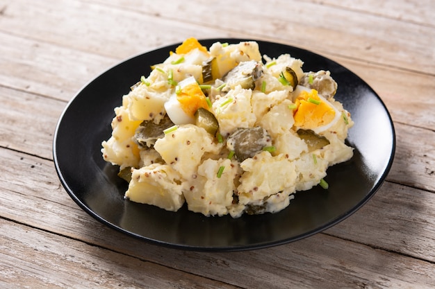 Salade de pommes de terre aux cornichons, oeuf et moutarde sur table en bois