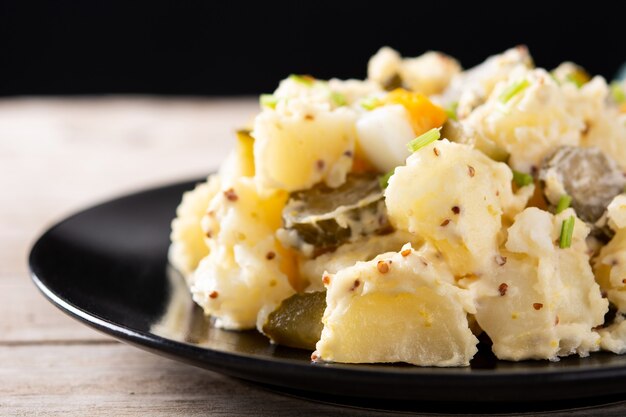 Salade de pommes de terre aux cornichons, oeuf et moutarde sur table en bois