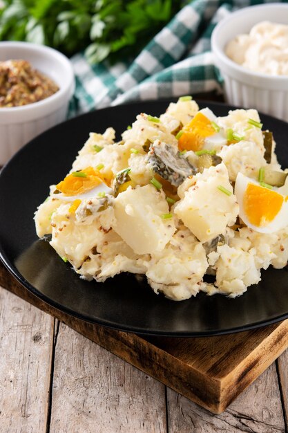 Salade de pommes de terre aux cornichons, oeuf et moutarde sur table en bois