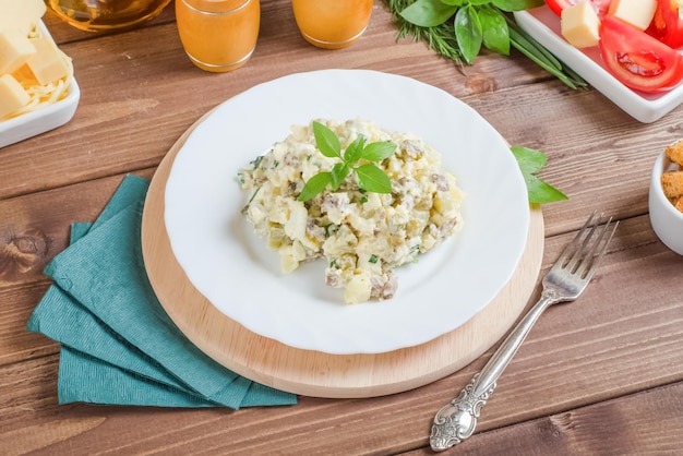 Photo salade de pommes de terre bouillies avec du boeuf bouilli et des oeufs assaisonnés de mayonnaise dans une assiette blanche sur fond bois foncé