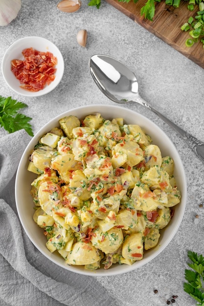 Photo salade de pommes de terre, œufs, bacon et herbes fraîches avec mayonnaise et sauce au yogourt dans un bol