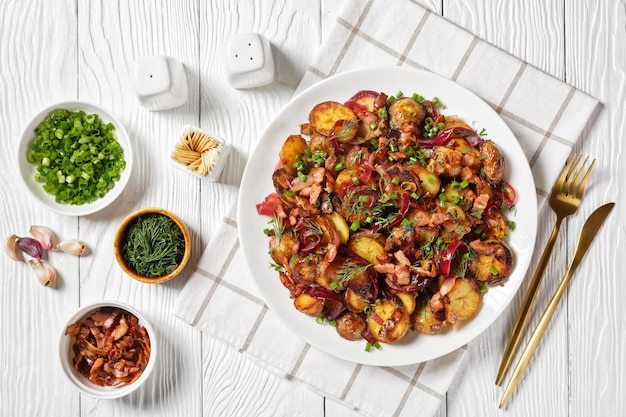 Salade de pommes de terre rôties Bratkartoffelsalat avec oignon rouge et bacon sur une assiette blanche sur une table en bois télévision lay cuisine allemande