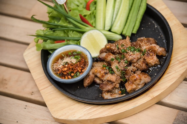 Salade de porc grillé chaud et épicé (Nam tok moo) sur la table en bois