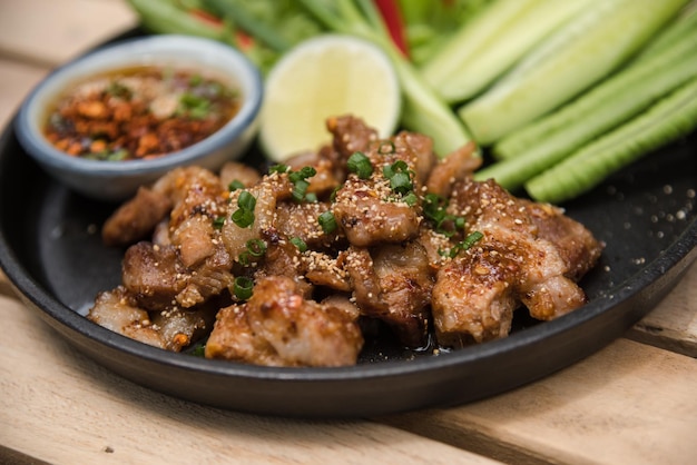 Salade de porc grillé chaud et épicé (Nam tok moo) sur la table en bois