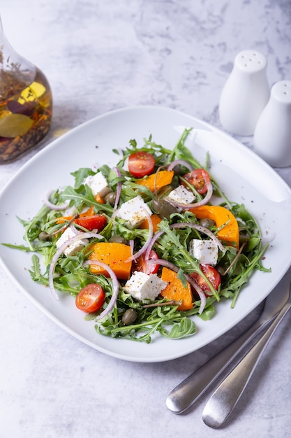 Salade de potiron, fromage feta, tomates, câpres, roquette et oignon rouge