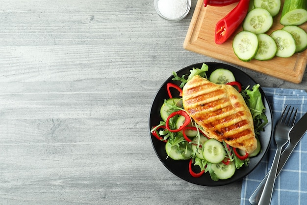 Salade de poulet grillé sur table texturée grise