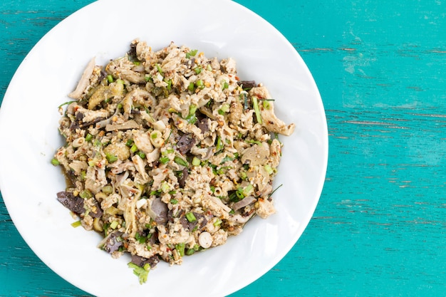 Salade de poulet haché épicé sur une table en bois bleue