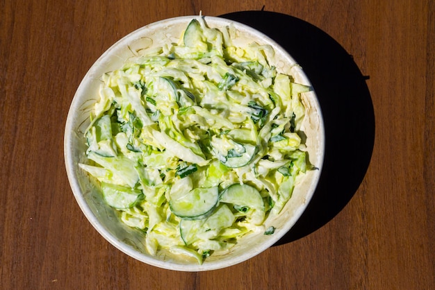 Salade printanière au chou, concombre, oignon vert, persil et mayonnaise sur table en bois