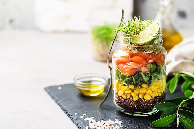 Salade printanière fraîche avec saumon, quinoa, roquette, salade de cresson et maïs dans un pot Mason.