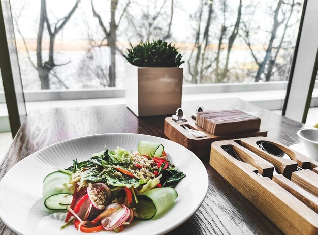 Photo salade printanière végétale dans une belle assiette en porcelaine blanche sur une table en bois dans un café