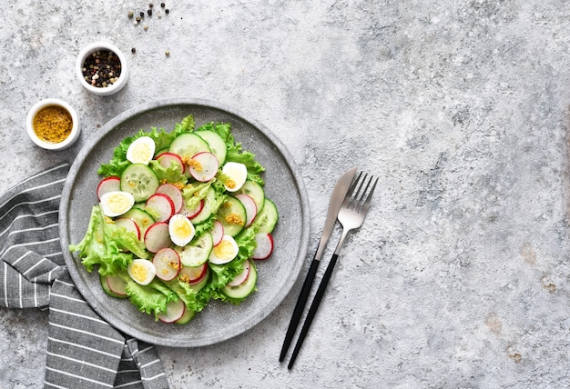 Salade de printemps aux oeufs et feuilles de salade sur une plaque de béton