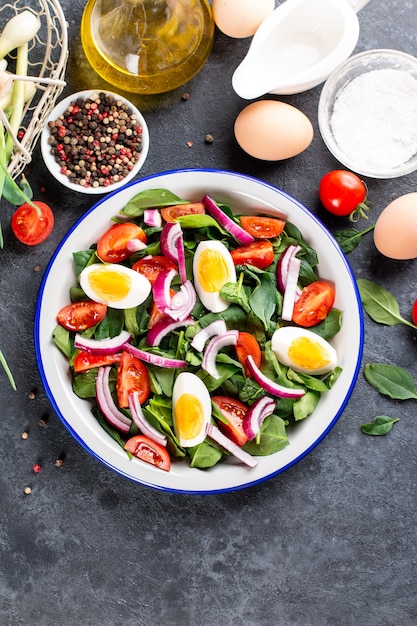 Salade de printemps. Salade de feuilles d'épinards, tomates et œuf dur. Nutrition adéquat. Alimentation saine. Le goût de l'été. Ingrédients crus dans une collation