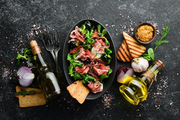 Salade de prosciutto aux olives dans un bol noir Cuisine espagnole Vue de dessus Espace libre pour votre texte Style rustique