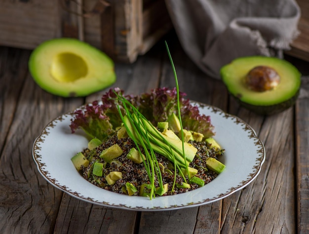 Salade de quinoa à l'avocat sain servi dans un plat isolé sur la vue latérale de fond en bois