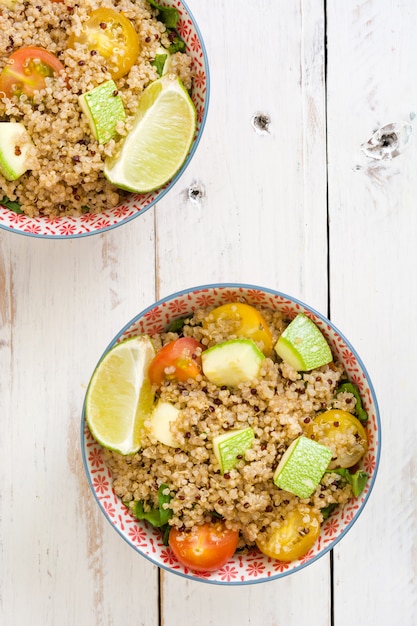 Salade de quinoa dans un bol sur une table en bois blanc