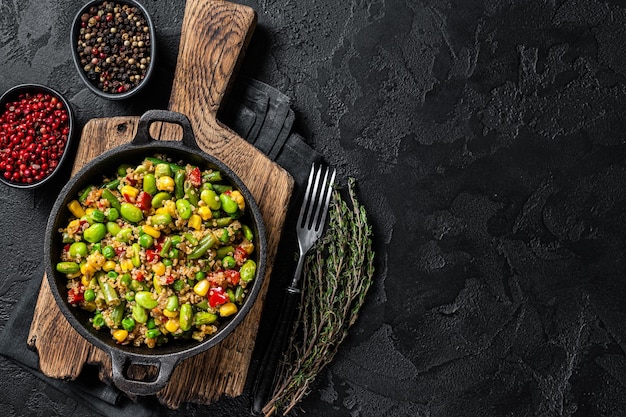 Salade de quinoa frit végétarien avec edamame maïs carotte tomate paprika oignons dans une casserole Fond noir Vue de dessus Copier l'espace