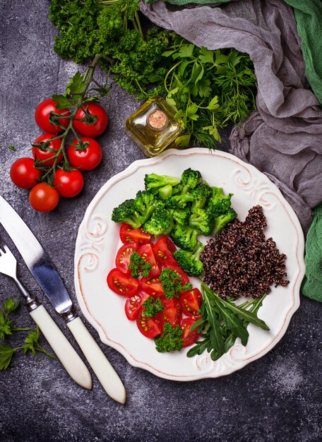 Salade de quinoa noir, tomates cerises, brocoli et roquette. Nourriture végétalienne saine