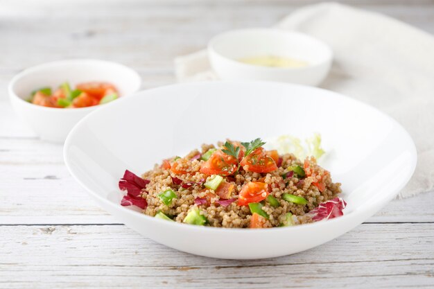 Salade de quinoa rustique sain avec des légumes sur une table en bois blanc