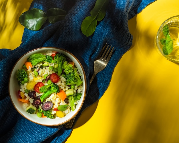 Salade de riz et de légumes de style marocain sur fond jaune et bleu