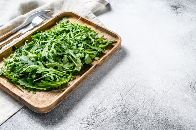 Salade de roquette fraîche dans un bol en bois. Surface grise. Vue de dessus. Espace copie