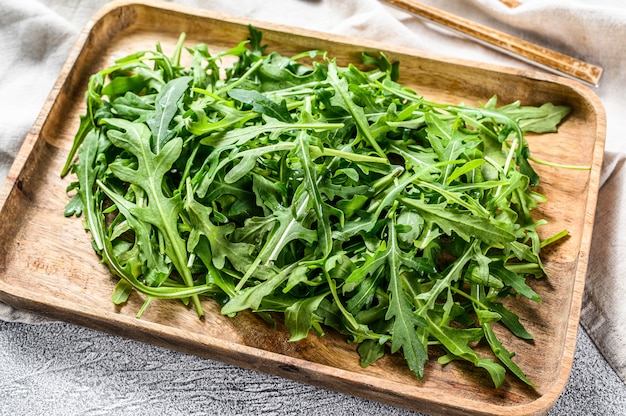 Salade de roquette fraîche dans un bol en bois. Surface grise. Vue de dessus