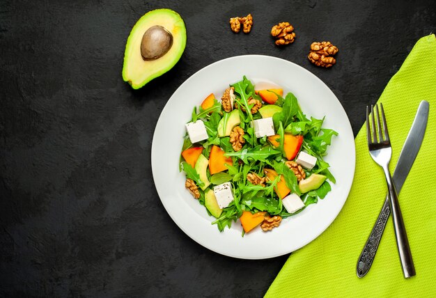 Salade de roquette, fromage, betterave, noix, sur fond d'ardoise, de pierre ou de béton.