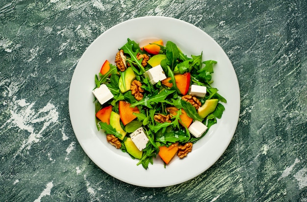 Salade de roquette, fromage, betterave, noix, sur fond d'ardoise, de pierre ou de béton.