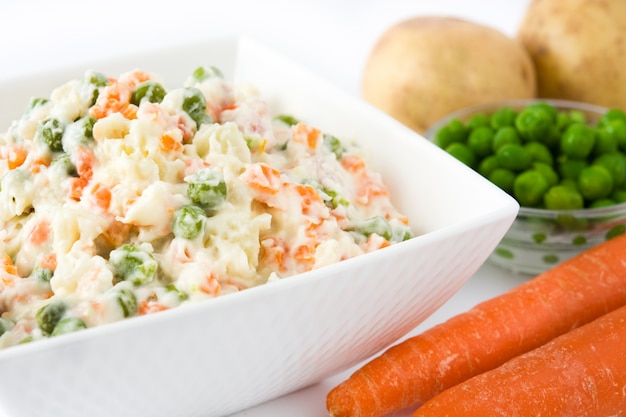 Salade russe dans un bol et ingrédient isolé sur blanc