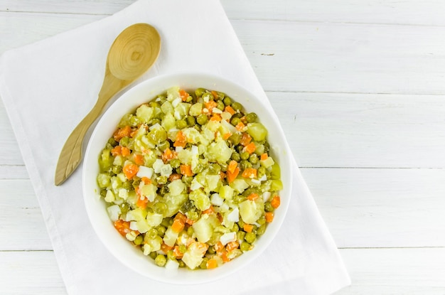 Salade russe Olivier avec pommes de terre carottes pois verts sur fond blanc