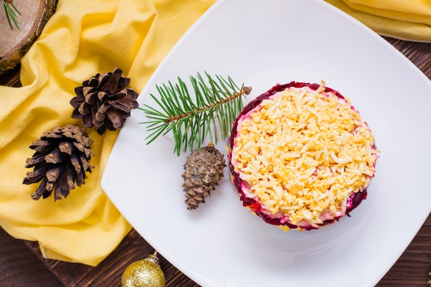 Salade russe traditionnelle - hareng sous un manteau de fourrure dans une assiette. Décoration de Noël. Vue de dessus