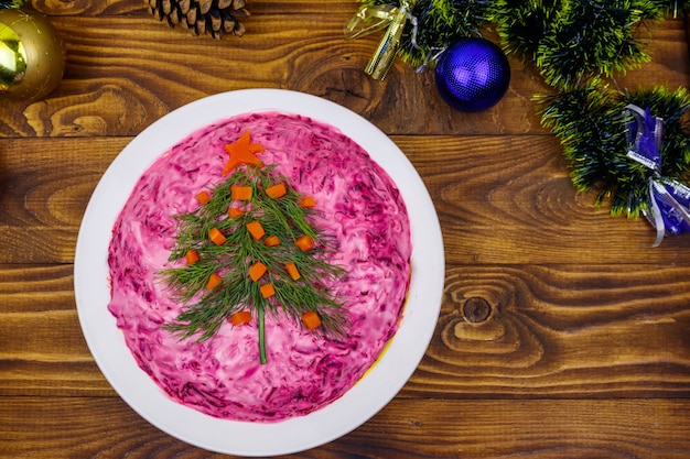 Salade russe traditionnelle Hareng sous un manteau de fourrure shuba et décorations de Noël sur table en bois