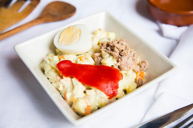 La salade russe traditionnelle ou salade Olivier est préparée avec des pommes de terre thon carottes et petits pois