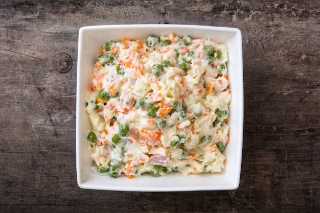 Salade russe sur la vue de dessus en bois rustique