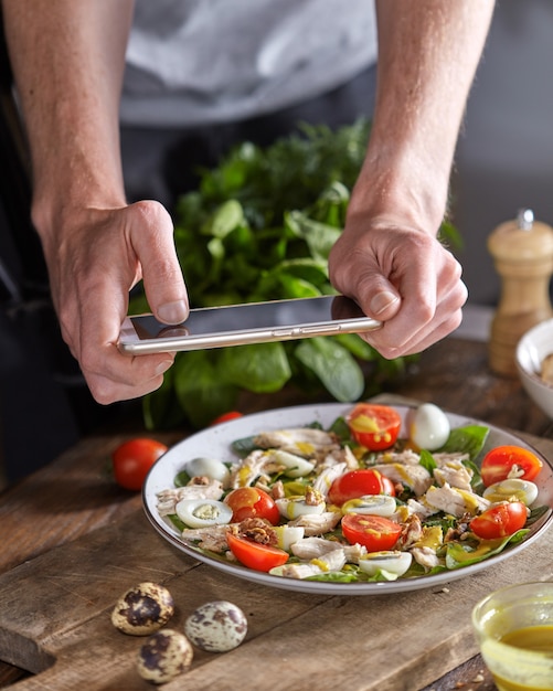 Salade saine appétissante à partir d'ingrédients biologiques dans une assiette avec la main des hommes faisant la photo par
