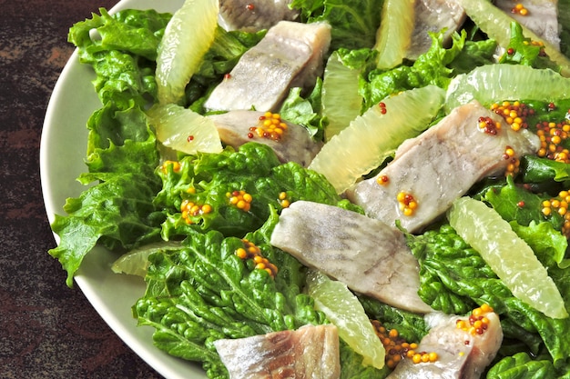 Salade saine aux feuilles vertes, hareng et citron. Salade de hareng au citron. Régime céto. Déjeuner ou dîner sain.