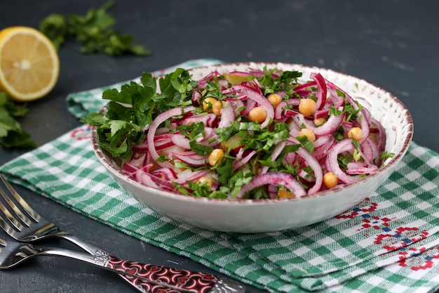 Salade saine aux pois chiches, pommes de terre, oignons rouges et concombres marinés dans une assiette