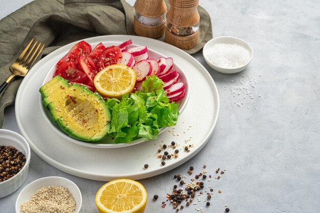 Salade saine aux radis, laitue tomate sur fond de béton gris.