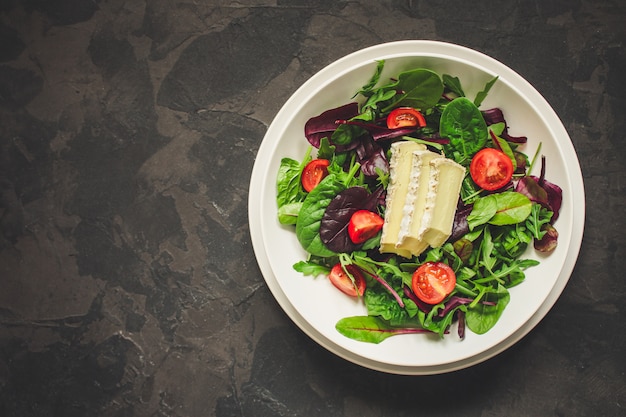 Salade saine feuilles dans une assiette blanche et du fromage (mélanger les micro-verts, collation juteuse). fond de nourriture